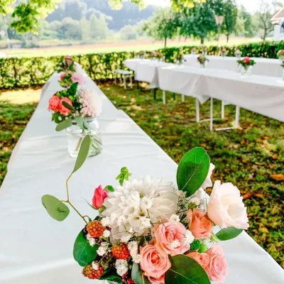 Lange Hochzeitstafel im Freien mit floraler Tischdekoration in Rosé und Weiß